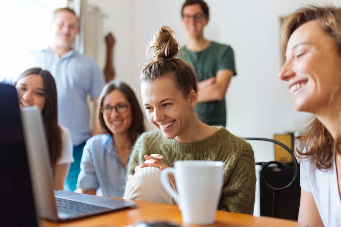 Eine Gruppe von Menschen sieht gemeinsam auf einen Laptopbildschirm